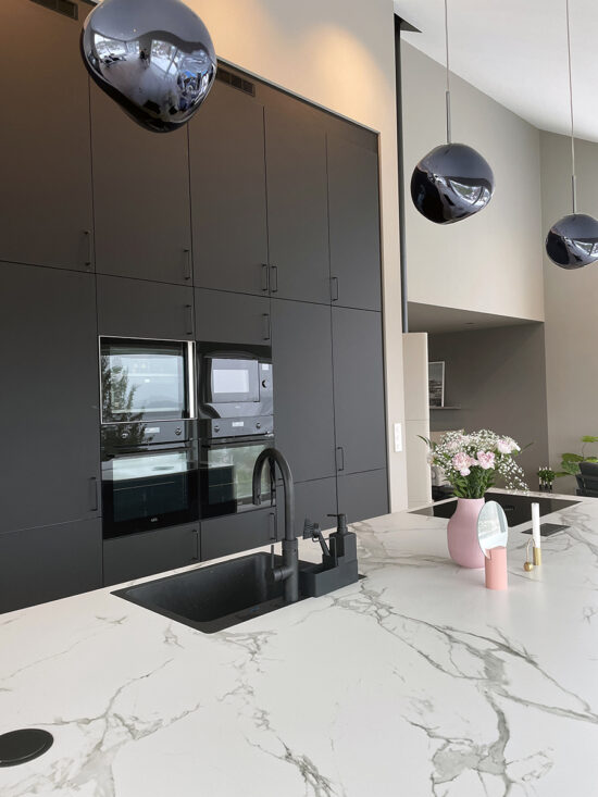 aubo sense køkken i sort med marmorbordplade og højskabsvæg